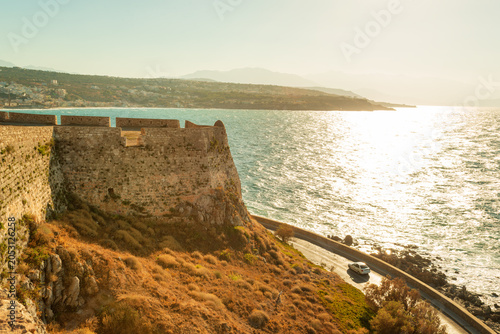Car driving around medieval defensive walls of Fortezza, old Venetian fortress in Rethymno, Crete, Greece