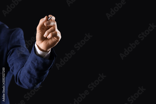 Businessman writing on dark...