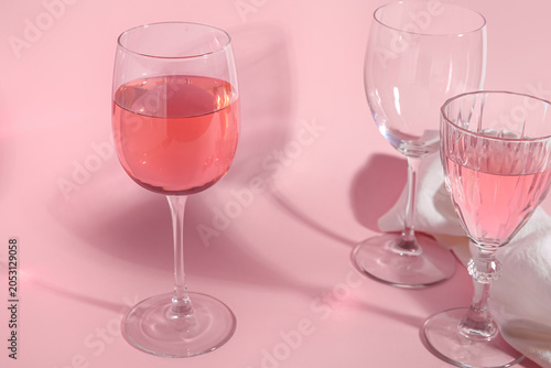 Glasses of wine on pink bac...