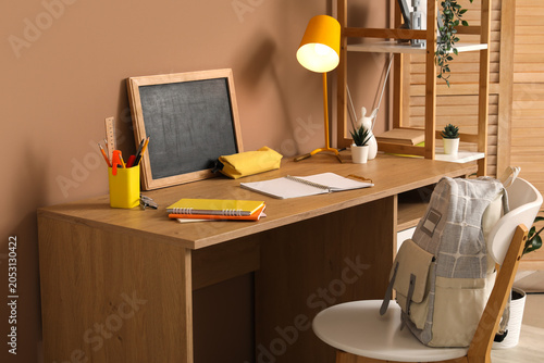 Student's workplace with chalkboard, lamp and stationery in room