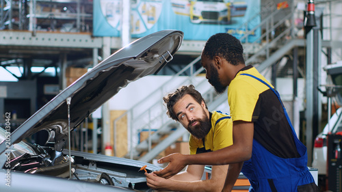 Foto Mechanics in auto repair shop working together on fixing car, discussing best options, with repairman and coworker collaborating on servicing broken vehicle, checking for faulty components