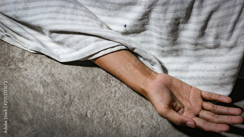 Bild auf Leinwand A crime scene concept showing a human hand lying lifeless  or dead body on the concrete floor, with the body covered by a white cloth fabric