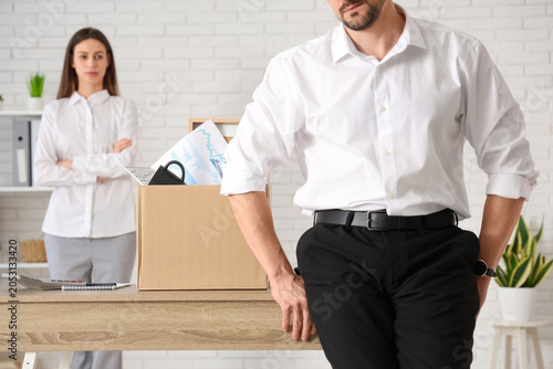 Fired young man with box of personal stuff and his colleague in office, closeup