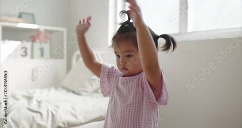 Cheerful Asian little Girl with Pigtails Dance in Cozy Minimalist Bedroom, morning light