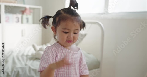 Cheerful Asian little Girl with Pigtails Dance in Cozy Minimalist Bedroom, morning light	