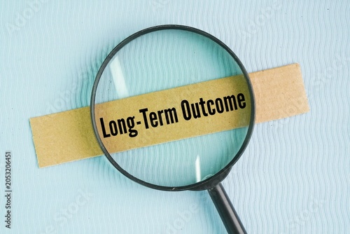 Foto Magnifying glass and box paper with the words Long-Term Outcome