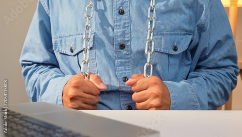 Obraz na płótnie A person tightly grips a heavy chain hanging around their neck, expressing discomfort and work-related stress