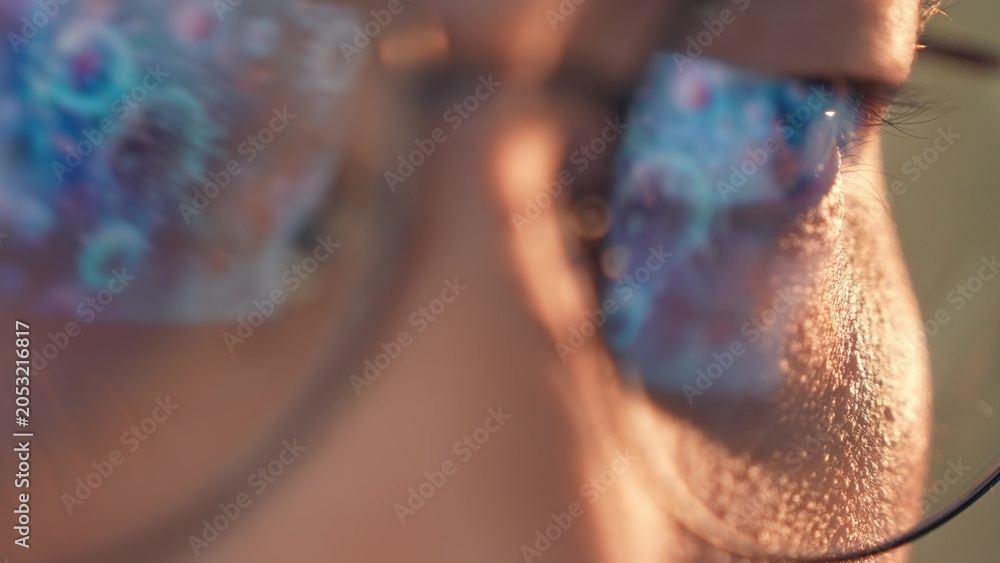 Fototapeta premium A person wearing glasses works on a laptop, with glowing reflections of viruses or bacteria in the lenses, symbolizing research, technology, health and broader conceptual ideas of science and society.