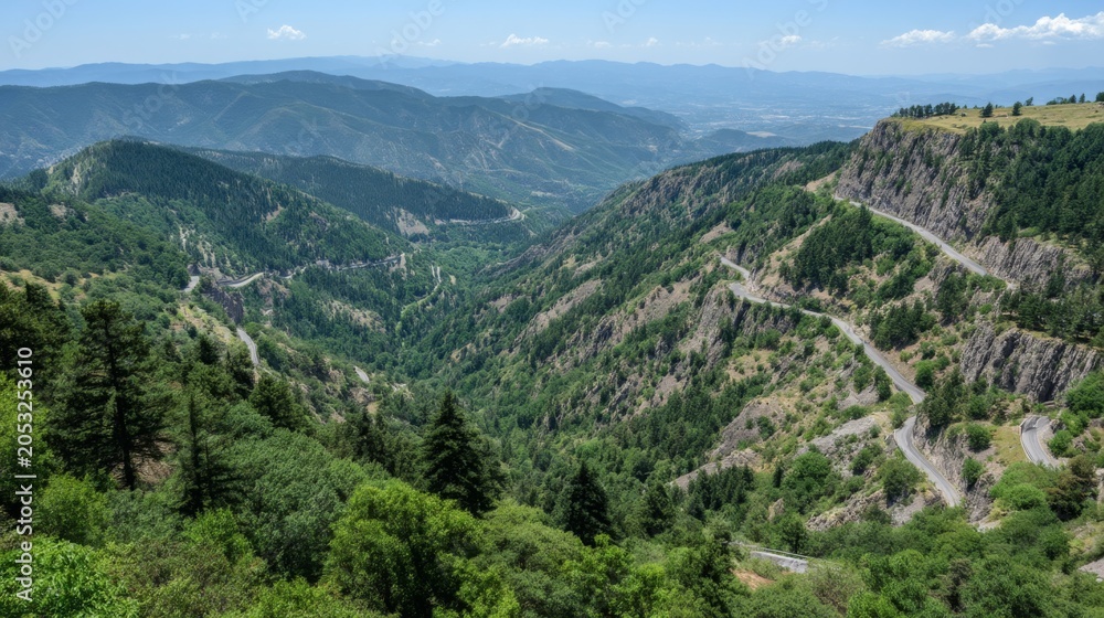 Fototapeta premium Scenic Mountain View Overlooking Lush Green Valley With Winding Road and Clear Blue Skies in Vibrant Daylight