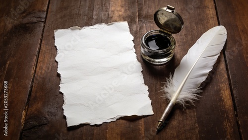  features a rustic, textured piece of white paper with rough, uneven edges, placed centrally on a rich, dark wooden surface. To the right of the paper, there is an open glass inkwell filled with black