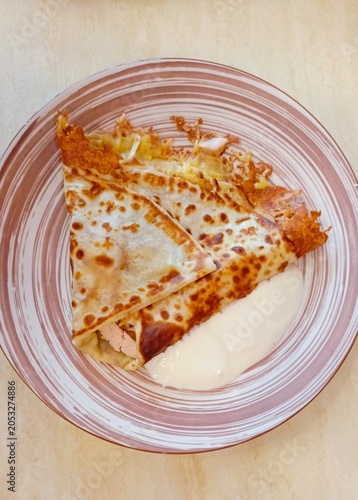 Fried Crepes with Meat Filling and Sour Cream on a Striped Plate – Savory Pancakes Close-up