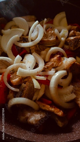 Fried Meat Pieces with Onions and Red Peppers in a Pan – Close-up Cooking Shot