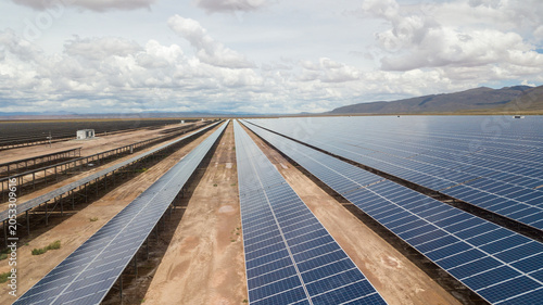 Fotografie Slow aerial drone shot of a solar panel farm in an arid landscape