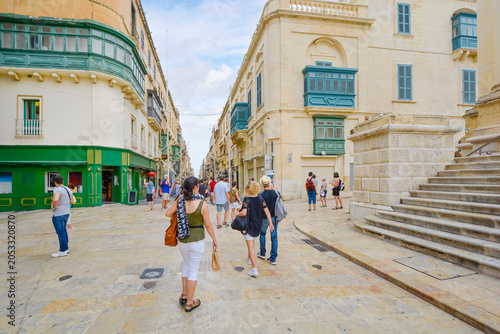 Tourists walk near the steps of the Royal Opera House on Republic Street, a major shopping area of limestone buildings and timber balconies in Valetta, Malta.