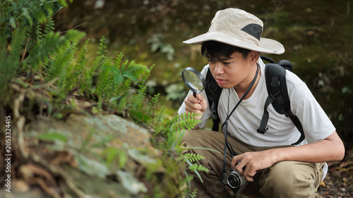 Young Nature Explorer Using Magnifying Glass to Study Plants in Forest Environment