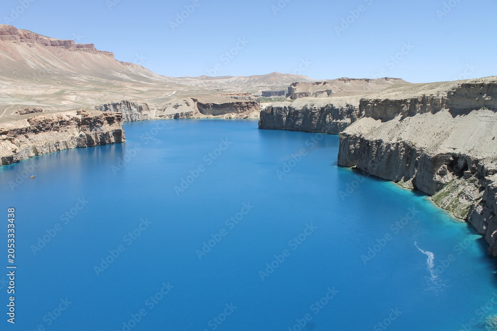 Fototapeta premium Band-e Amir National Park showcases Afghanistan’s breathtaking natural beauty with crystal-clear turquoise lakes, dramatic cliffs, and peaceful landscapes under a vibrant blue sky.