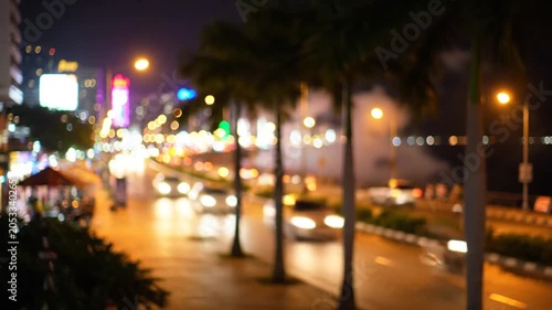 Blurry night city street with palm trees and bokeh lights