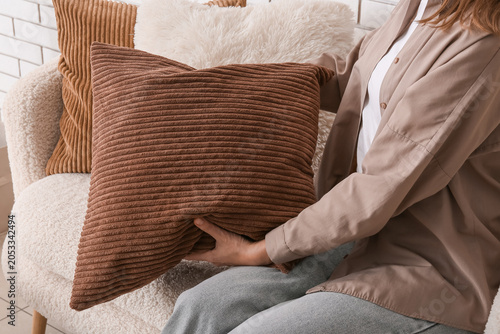 Foto Woman holding brown corduroy pillow on cozy armchair, home decor and interior de