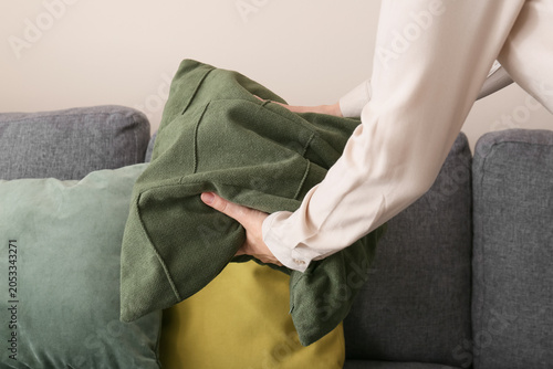 Foto Woman's hands arranging green decorative pillow on gray sofa, home interior comf