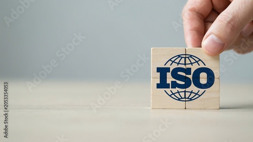 A close-up photo shows a hand placing a wooden block with the ISO logo on a table.