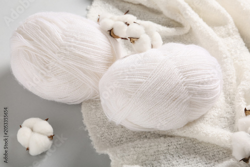 Fotografie Natural white cotton yarn skeins and raw cotton bolls on soft textile background