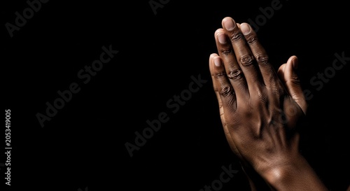 Close-up of African American Hands Praying Against a Black Background with Copy Space