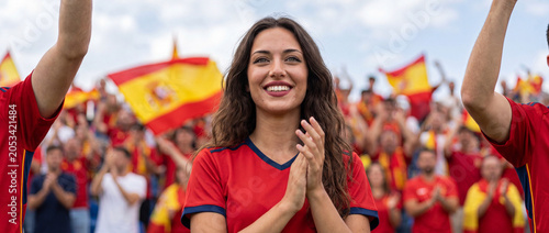 Beautiful Spanish female fan smiling and clapping at stadium