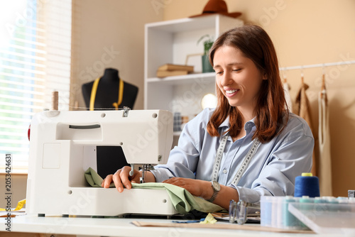 Smiling young woman sewing ...
