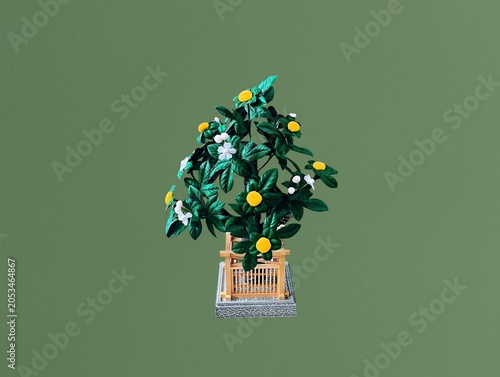 The green background in the image shows plastic flowers in a green wooden box. The flowers are white and yellow, made of plastic, and are used for decoration in homes or shops, offering a colorful dis