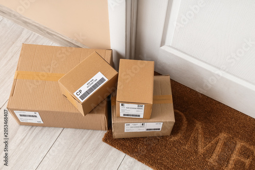 Foto Cardboard delivery boxes with shipping labels on doorstep, e-commerce and logist