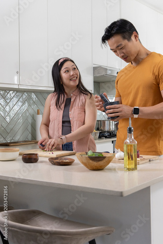 Diverse couple chopping and seasoning food at kitchen island with cutting board, olive oil bottle
