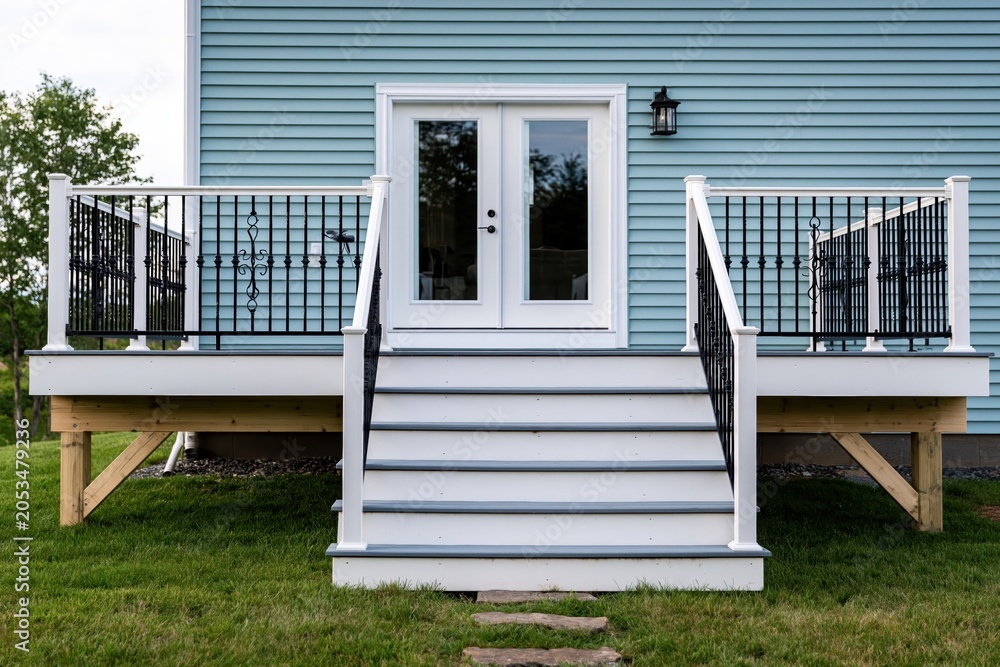 Fototapeta premium Deck with white stairs and railing in backyard patio of new home construction