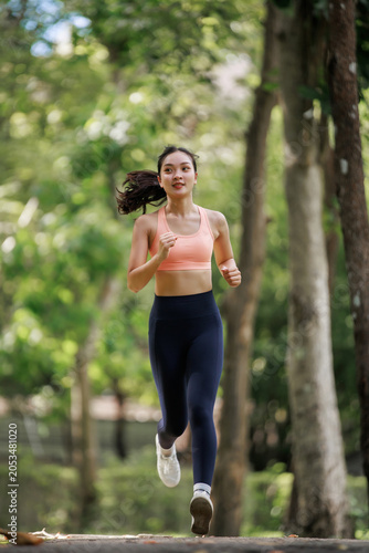 Young athletic woman running outdoors in a park, maintaining an active lifestyle and focusing on fitness and wellbeing