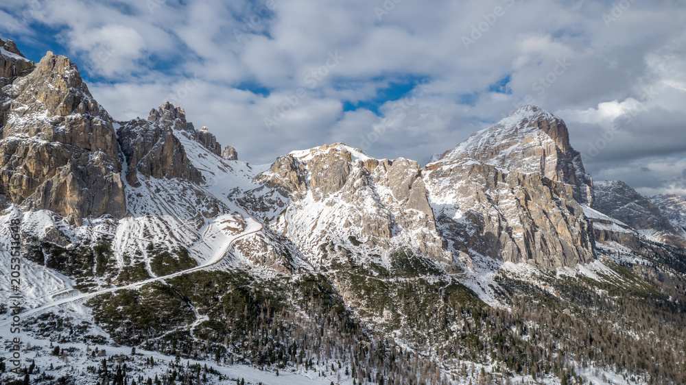 Obraz premium Aerial View of Falzarego Pass with Snowy Peaks and Winding Road, Dolomites, Italy