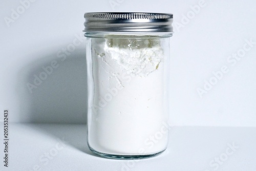Fotografi Maizena flour in glass jar with metal lid isolated on horizontal white background