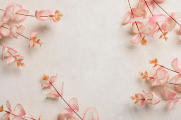 Pink eucalyptus leaves and branches on textured white background with copy space for botanical design, the composition provides ample copy space for text or additional elements