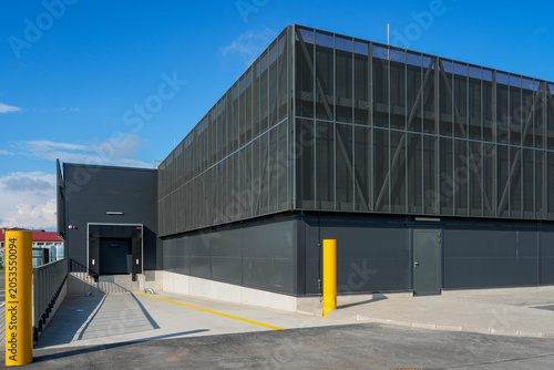Modern logistics warehouse loading dock with mesh facade and service access area exterior view