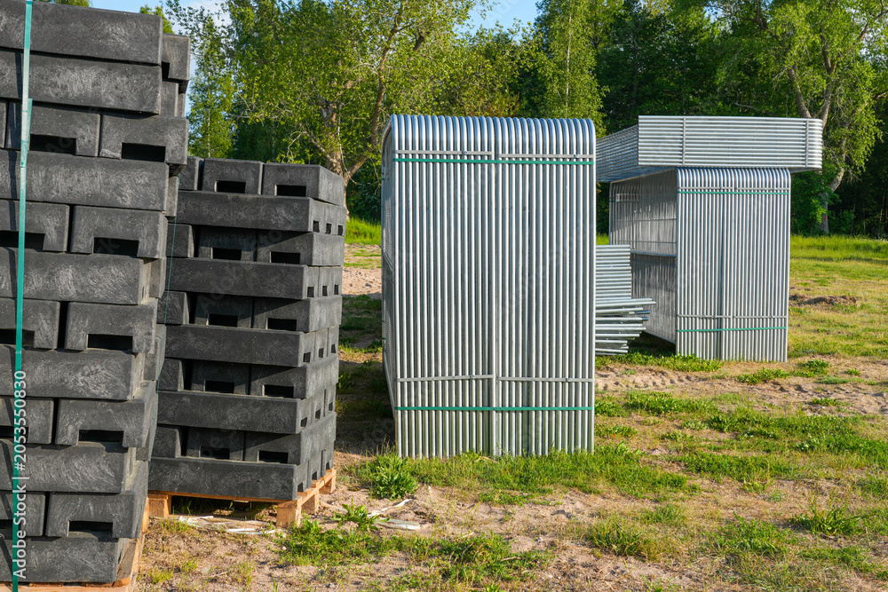 Fototapeta premium Temporary fencing panels and recycled plastic fence bases stored at construction site warehouse yard