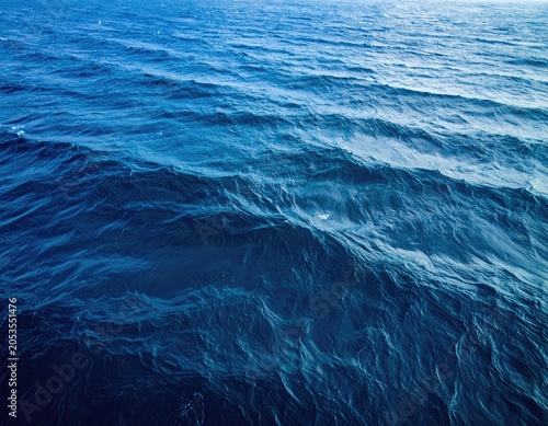 Aerial view of deep blue ocean waves gently rippling across the water's surface, reflecting sunlight