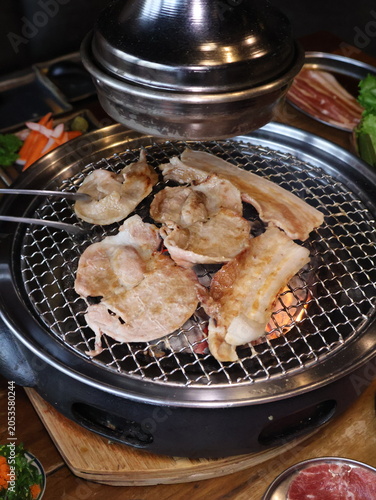 Fotografie Grilled pork sizzling over a charcoal barbecue.