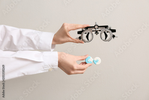Obraz na płótnie Doctor hands with optical trial frame and container of contact lenses on white b