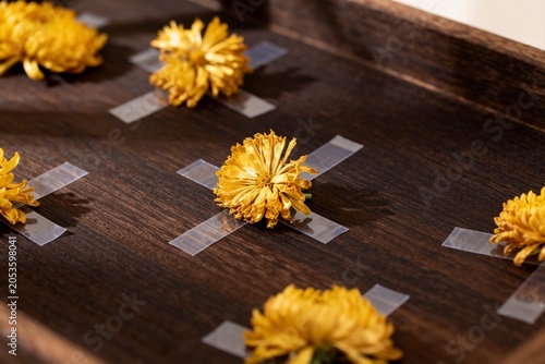Yellow flowers taped to a wooden board