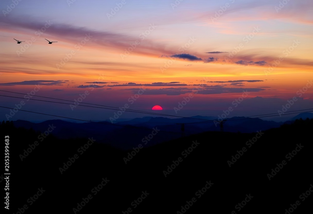 Obraz premium Set of diverse zipline silhouettes against sunset sky, cliff, sky