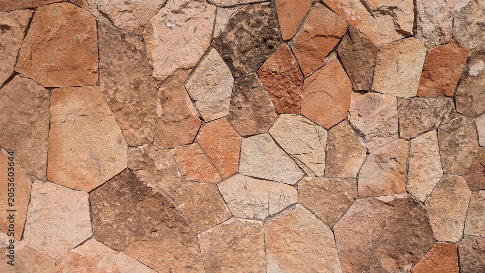 Fototapeta premium A close-up view of a rustic stone wall with irregularly shaped stones and natural textures.