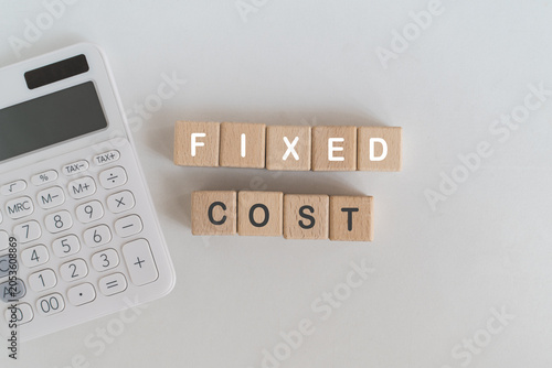 Canvastavla Fixed Cost text on wooden cube block and white calculator on white desk, top vie