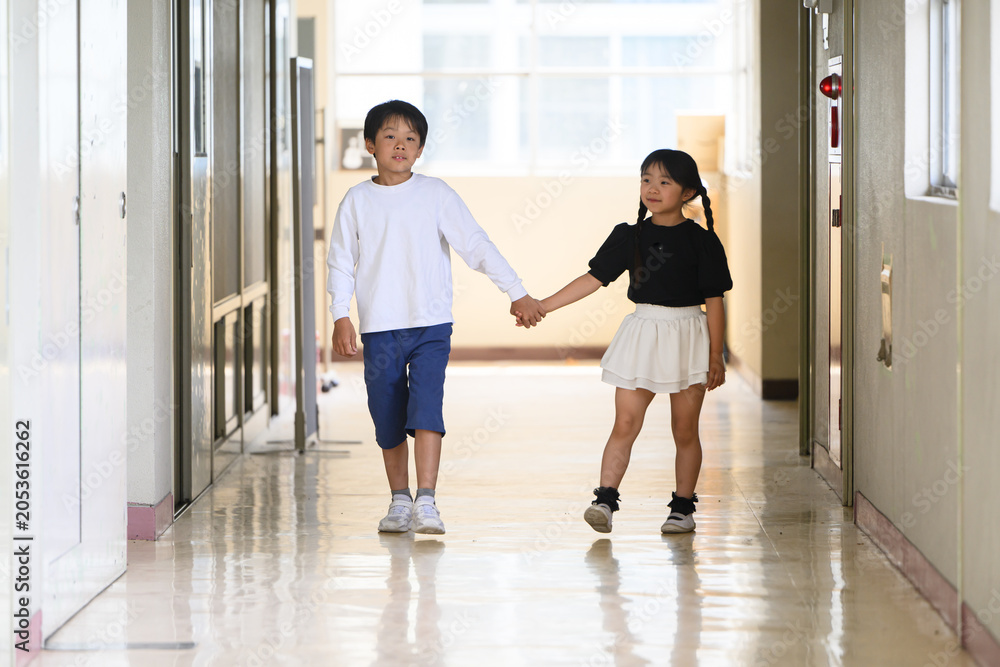 Fototapeta premium 学校の廊下で手をつないで新入生を案内する上級生