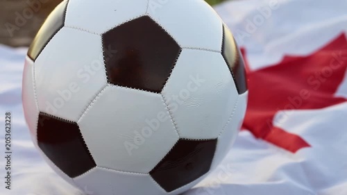A classic black and white soccer ball sits on a Canadian flag. This image represents the excitement for the 2026 World Cup, hosted by Canada, USA, and Mexico