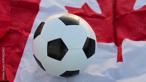 Soccer ball rests on a Canadian flag, representing the anticipation for the 2026 World Cup. The major sports event will be jointly hosted by Canada and the USA, bringing global football action