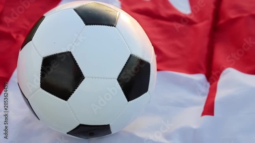 A classic black and white soccer ball sits prominently on a red and white Canadian flag. This image represents the upcoming 2026 World Cup hosted by Canada and the USA