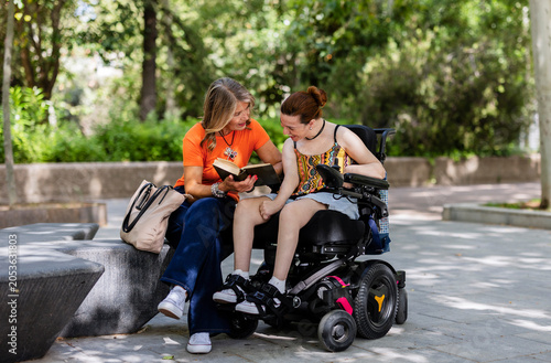 Foto Woman reading book to young woman in wheelchair